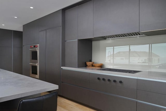 kitchen with gray cabinets, light hardwood / wood-style floors, black electric cooktop, and double oven