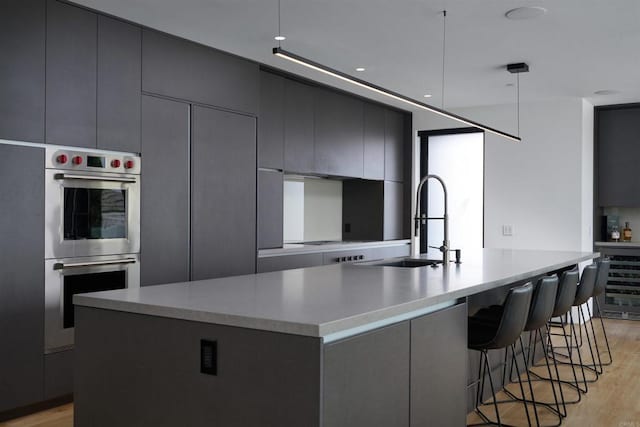 kitchen with double oven, beverage cooler, light hardwood / wood-style floors, and a large island