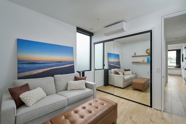 living room featuring a wall mounted air conditioner and light hardwood / wood-style floors