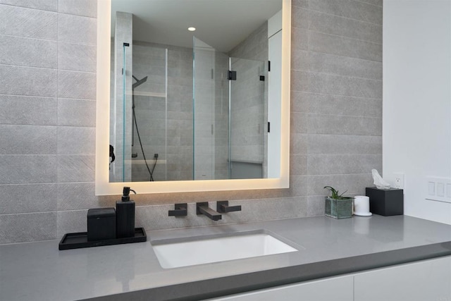 bathroom with tile walls, vanity, and tiled shower