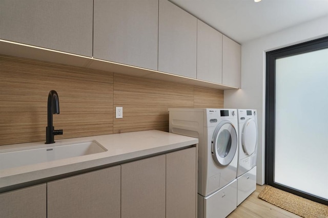 washroom featuring cabinets, light hardwood / wood-style flooring, sink, and washer and clothes dryer