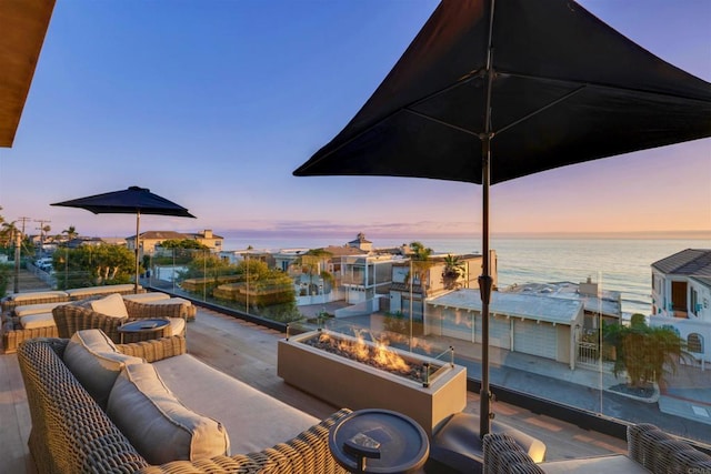 patio terrace at dusk with a water view and an outdoor living space with a fire pit