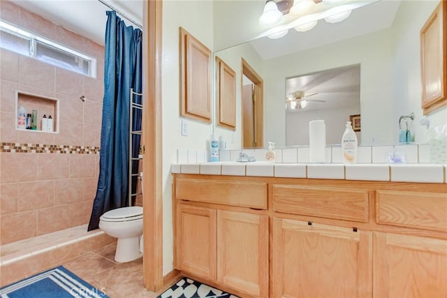 bathroom with ceiling fan, toilet, vanity, tiled shower, and tile patterned floors