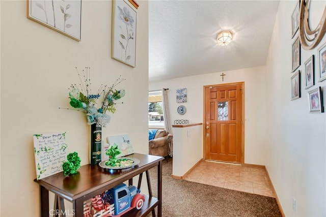 entrance foyer featuring light carpet, baseboards, and light tile patterned floors