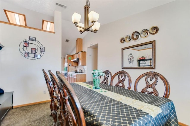 carpeted dining room with a chandelier, visible vents, high vaulted ceiling, and baseboards