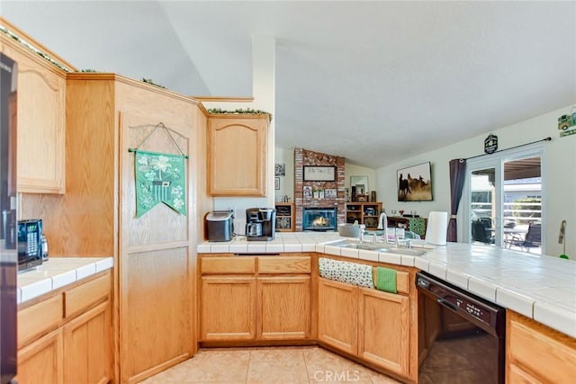 kitchen featuring lofted ceiling, light brown cabinets, a fireplace, a sink, and black dishwasher