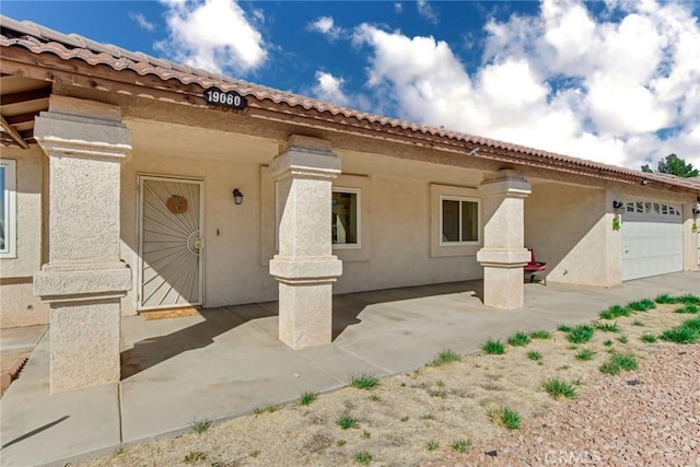 mediterranean / spanish-style home featuring a patio area, an attached garage, and stucco siding