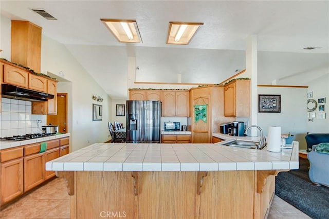 kitchen with gas stovetop, light tile patterned floors, under cabinet range hood, a peninsula, and stainless steel fridge with ice dispenser