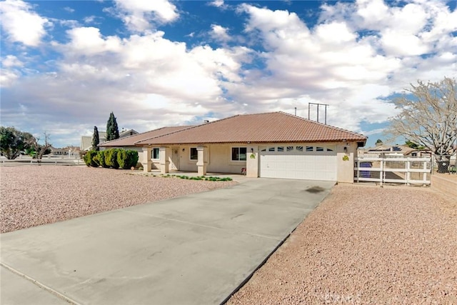 view of front of property featuring a tile roof, stucco siding, fence, a garage, and driveway