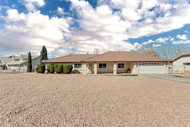 ranch-style house featuring stucco siding, fence, a garage, driveway, and a tiled roof