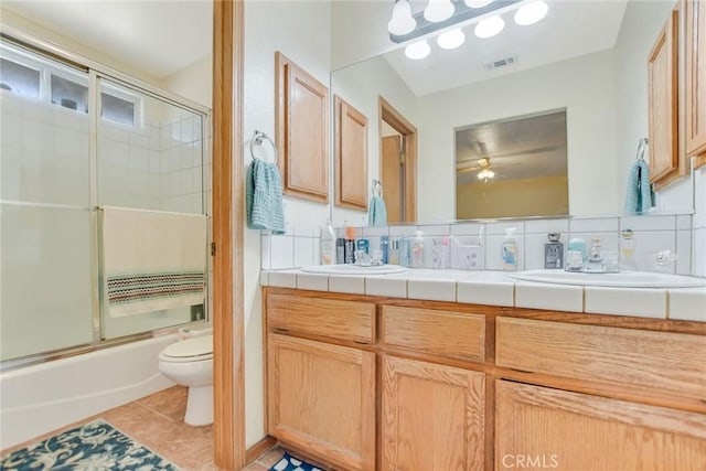 full bath with combined bath / shower with glass door, a sink, toilet, and tile patterned floors