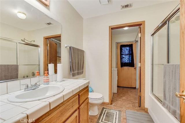 bathroom featuring visible vents, a shower with door, vanity, and toilet