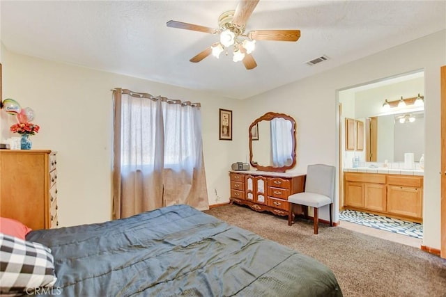 bedroom featuring baseboards, visible vents, a ceiling fan, light colored carpet, and ensuite bathroom