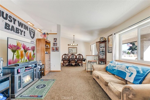 carpeted living area with a notable chandelier and vaulted ceiling