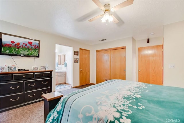 bedroom with visible vents, a ceiling fan, connected bathroom, carpet floors, and two closets