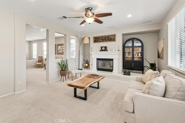 living room featuring baseboards, visible vents, light colored carpet, and a glass covered fireplace