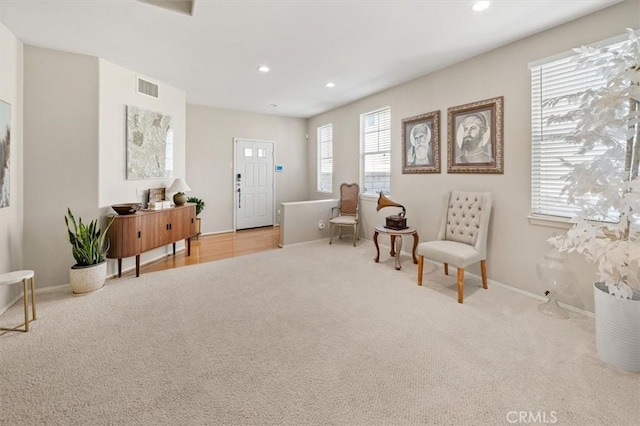 sitting room with light colored carpet, visible vents, and recessed lighting