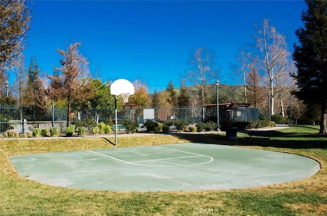 view of sport court featuring community basketball court, fence, and a lawn