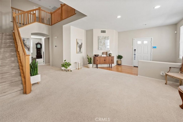 entryway featuring arched walkways, recessed lighting, light colored carpet, visible vents, and stairs