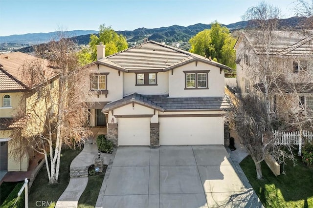 view of front of home featuring driveway, a tile roof, a chimney, a mountain view, and stucco siding