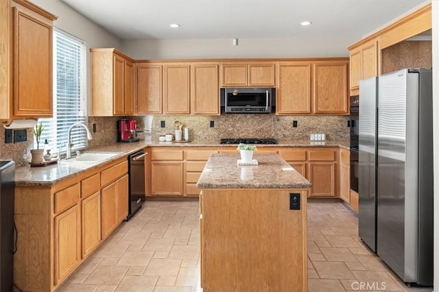 kitchen with light stone counters, a sink, backsplash, a center island, and black appliances