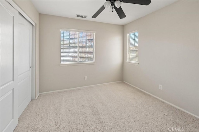 unfurnished bedroom featuring light carpet, baseboards, visible vents, a ceiling fan, and a closet