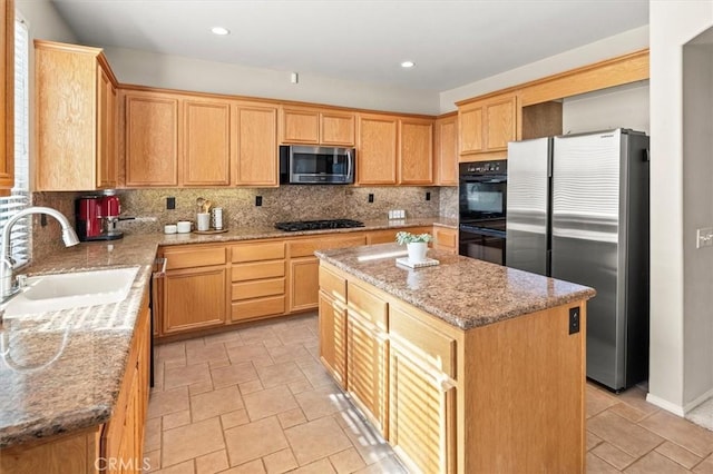 kitchen with appliances with stainless steel finishes, light stone counters, a sink, and a center island