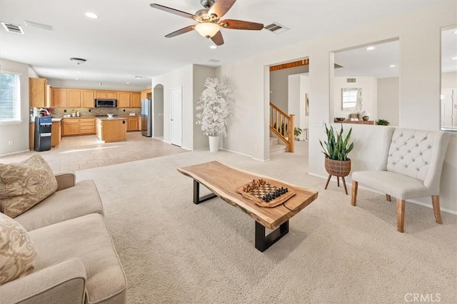 living room featuring light carpet, visible vents, arched walkways, stairway, and recessed lighting