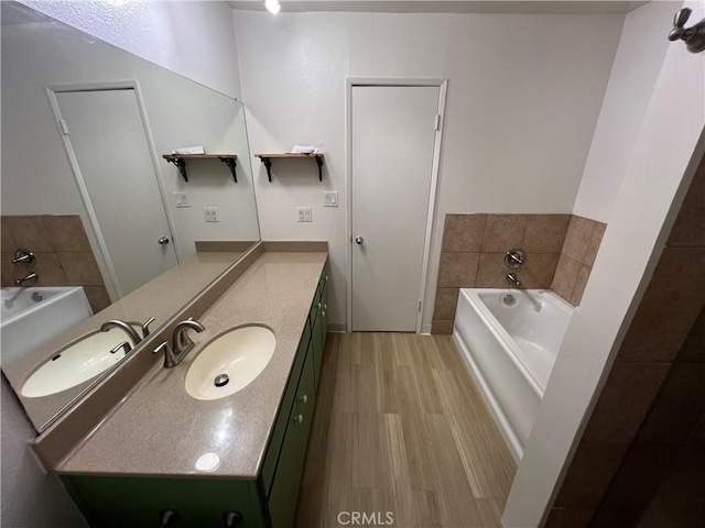 bathroom with a garden tub, wood finished floors, and vanity