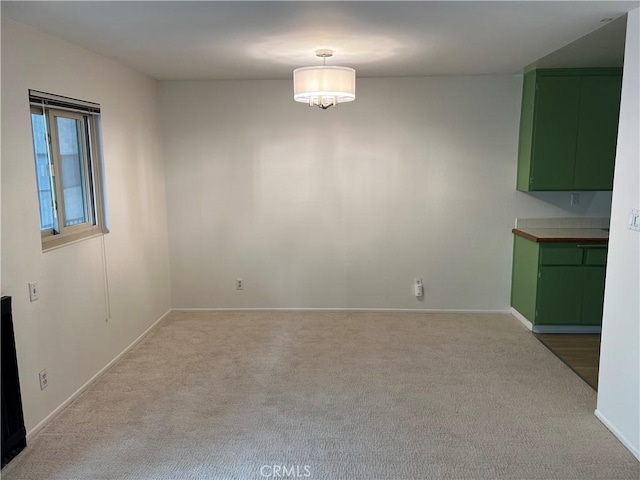 unfurnished dining area featuring carpet flooring and baseboards