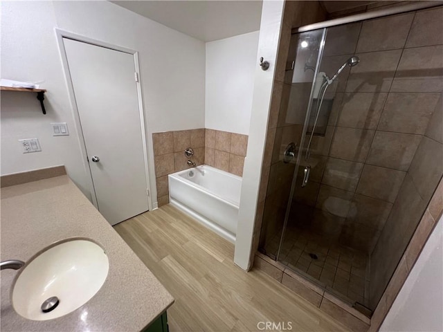 full bath with wood finished floors, a shower stall, a garden tub, and vanity