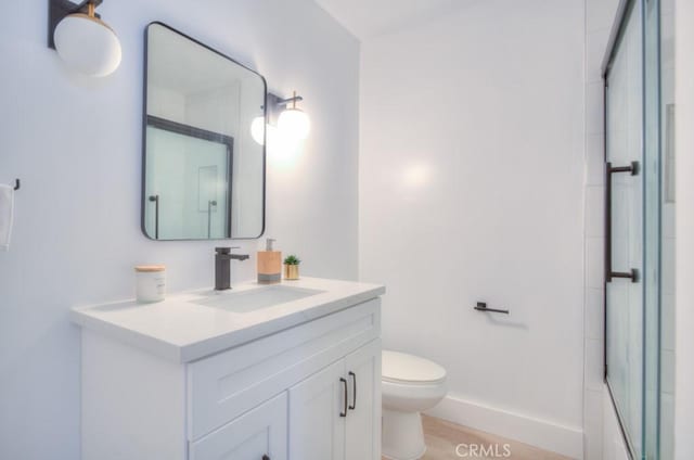 bathroom featuring toilet, vanity, walk in shower, and hardwood / wood-style floors