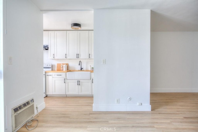 interior space featuring sink, white cabinets, a wall mounted AC, and wood counters