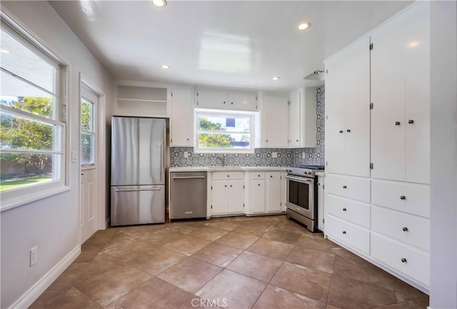 kitchen with stainless steel appliances, backsplash, sink, white cabinetry, and a healthy amount of sunlight