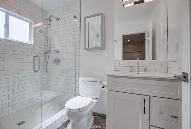 bathroom with toilet, vanity, and a shower with shower door