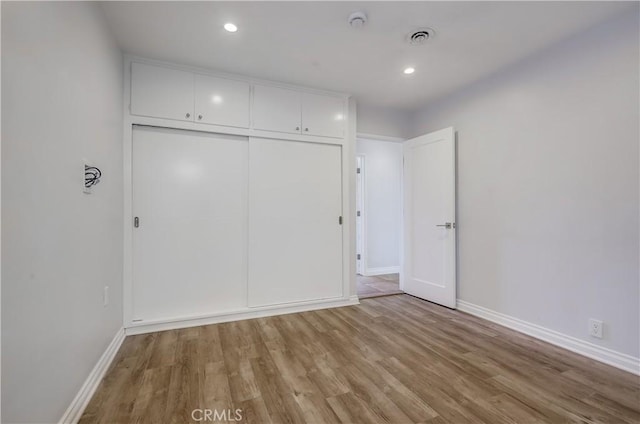 unfurnished bedroom with light hardwood / wood-style flooring and a closet