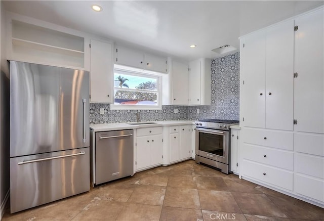 kitchen featuring sink, backsplash, white cabinetry, and premium appliances