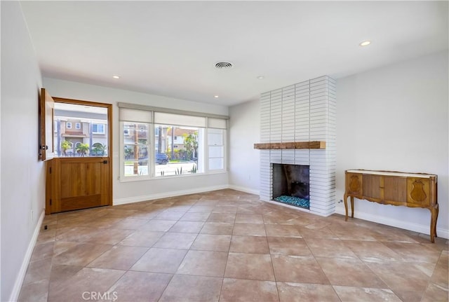 unfurnished living room featuring light tile patterned floors and a brick fireplace