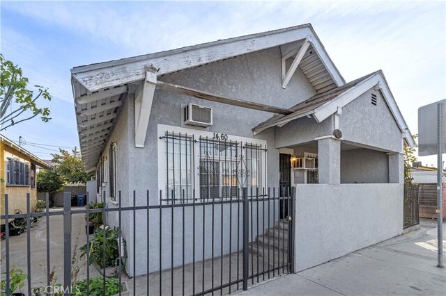 view of front of home featuring a fenced front yard, a wall mounted AC, a gate, and stucco siding