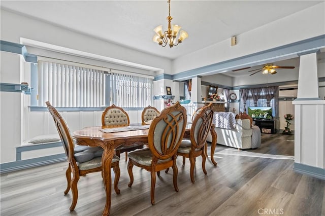 dining space with ceiling fan with notable chandelier and wood finished floors