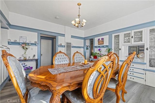 dining area with dark wood-style floors and a notable chandelier