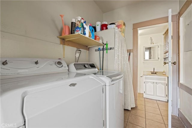 washroom featuring a sink, laundry area, light tile patterned flooring, and washing machine and dryer