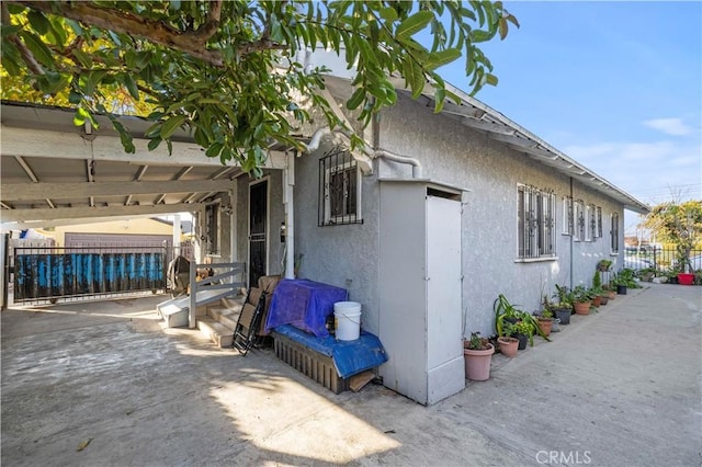 view of property exterior with a patio, fence, and stucco siding