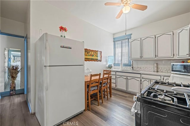 kitchen featuring stainless steel appliances, wood finished floors, a ceiling fan, light countertops, and tasteful backsplash