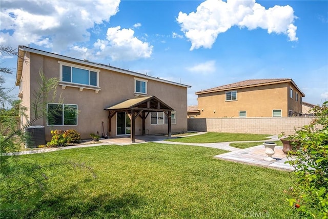 rear view of property featuring central AC unit, a yard, a gazebo, and a patio area