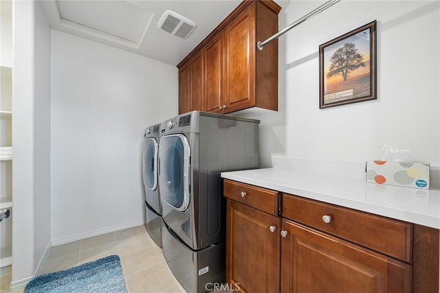 clothes washing area with washing machine and clothes dryer, light tile patterned flooring, and cabinets