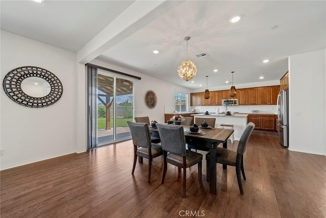 dining room with a chandelier, beamed ceiling, and dark hardwood / wood-style floors