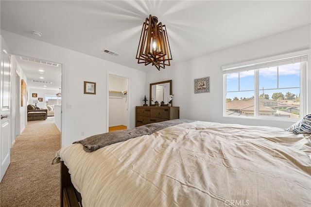 carpeted bedroom featuring a notable chandelier and a spacious closet