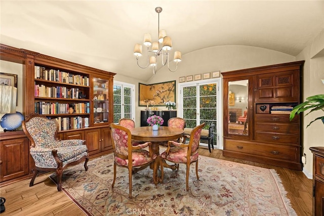 dining space with a chandelier, vaulted ceiling, and light wood finished floors