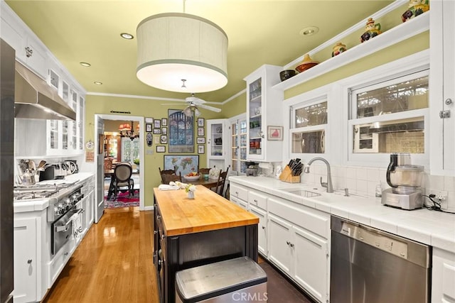 kitchen featuring tile countertops, white cabinetry, stainless steel dishwasher, glass insert cabinets, and pendant lighting